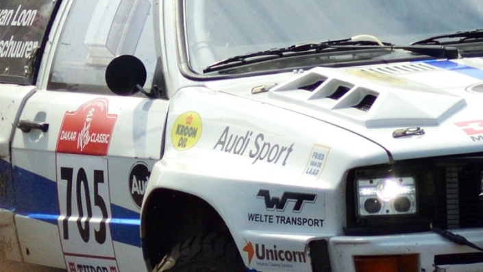 Rally car 705 Eric van Loon coming around the curve large cloud of dust kicked up behind him grid tile 5