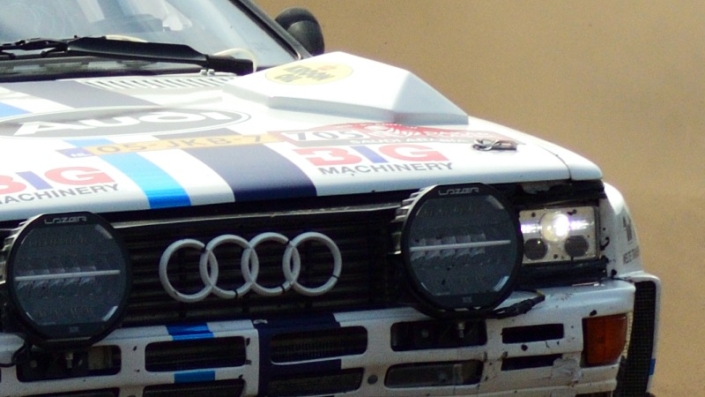 Rally car 705 Eric van Loon coming around the curve large cloud of dust kicked up behind him grid tile 6