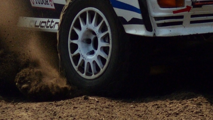 Rally car 705 Eric van Loon coming around the curve large cloud of dust kicked up behind him grid tile 8