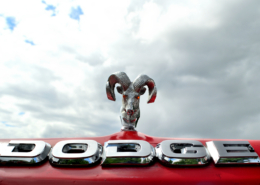Red Dodge Truck with ram hood ornament and light up eyes. Cloudy overcast sky in the background.